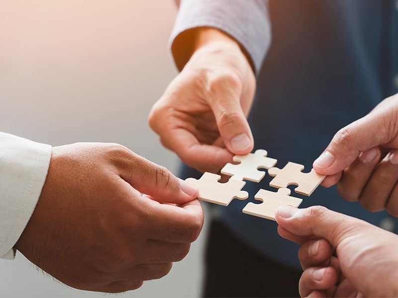 Mãos segurando peças de quebra-cabeça se encaixando, simbolizando a colaboração e parceria nas estratégias de growth marketing.
